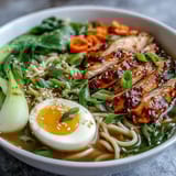 Healthy Miso Chicken Noodle Bowls topped with soft-boiled eggs, crisp bok choy, and sesame seeds for a comforting meal.