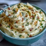 Creamy garlic aioli, a homemade mayonnaise with bold garlic flavor, served in a rustic bowl with fresh herbs.