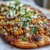 Mexican-inspired flatbread topped with smoky grilled corn, fresh cilantro, and creamy jalapeño sauce, perfect for festive gatherings.  