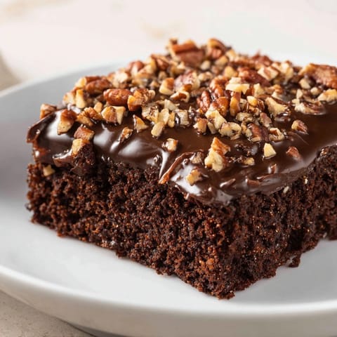 Warm, fudgy Texas sheet cake with smooth, glossy chocolate icing on a baking sheet.