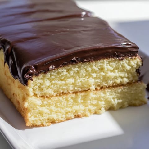 Rich, glossy chocolate ganache coats this Ho Ho Cake, promising a truly satisfying dessert.