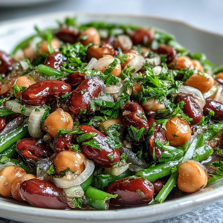 Healthy Three-Bean Salad ready for a potluck, showing a vibrant mix of beans and diced red onion in a glass serving dish.