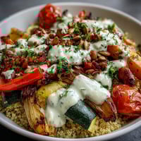 Golden-brown roasted vegetables and fluffy quinoa in a white bowl, drizzled with creamy tahini sauce for the Roasted Vegetable Quinoa Bowl.