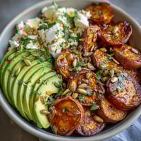 Golden roasted sweet potato cubes with crispy edges sit beside creamy avocado slices and cottage cheese in this vibrant Hot Honey Sweet Potato Bowl.